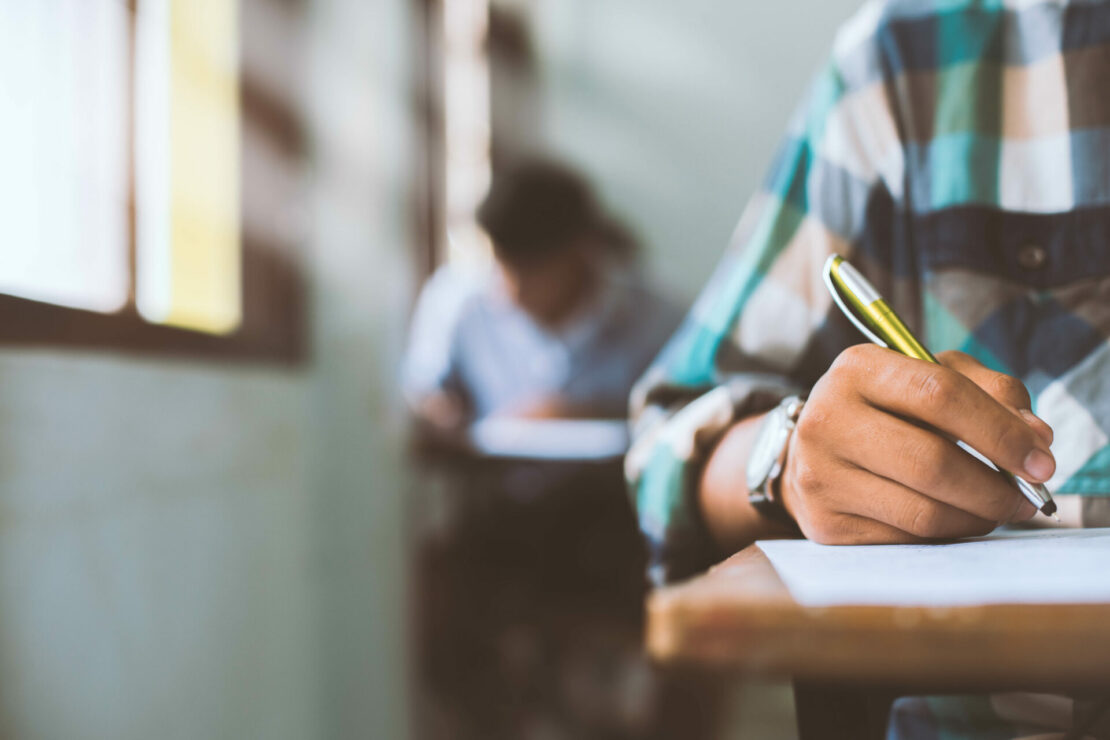 Close up Students writing and reading exam answer sheets exercises.